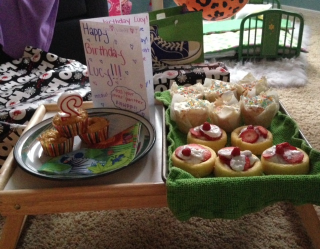 The cat cakes are placed  next to the human strawberry shortcakes and cupcakes. 